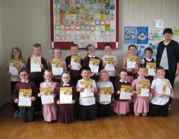 Primary 4 pupils receive their First Communion certificates.